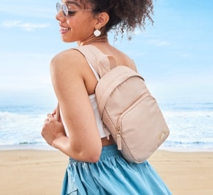 Woman wearing beige travel bag on the beach for vacations